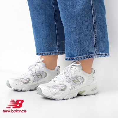 Ténis New Balance brancos com detalhes cinzentos usados com calças azuis