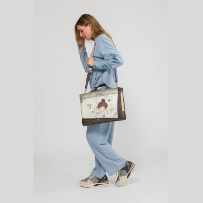 Mulher com fato de treino azul claro e ténis azuis, com mala ilustrada castanha e bege