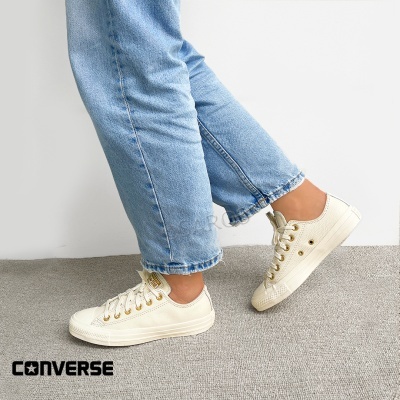 Tênis Converse em pele branca com sola branca e ilhós dourados.