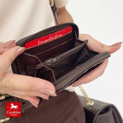 Carteira de couro castanha escura aberta mostrando interior com divisórias e cartão vermelho