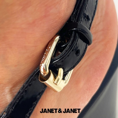 Fivela dourada em correia preta de sapato com marca JANET & JANET.