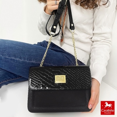 Mala preta elegante com detalhes dourados e alça em corrente sobre fundo branco.