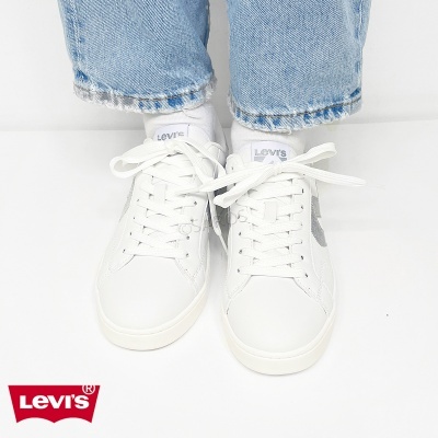 Ténis Levis brancos com atacadores usados com meias brancas e calças de ganga