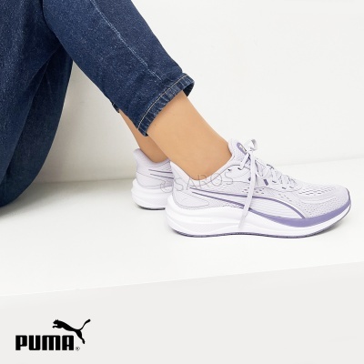 Ténis Puma brancos e lilás em malha com sola robusta usados por pessoa com jeans