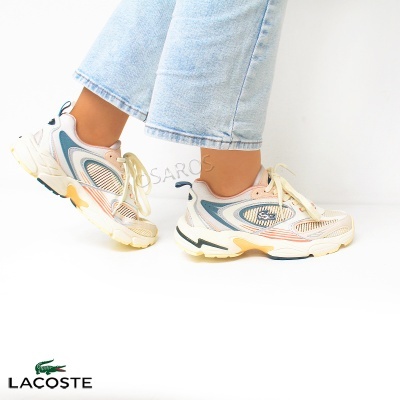 Ténis Lacoste coloridos com sola branca usados com jeans claros num fundo branco