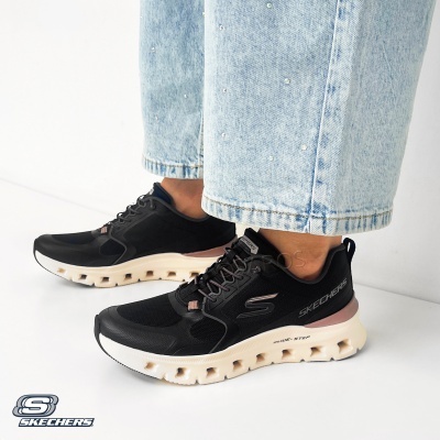 Sapatilhas Skechers pretas com sola branca e rosa, usadas com jeans azuis claros com cristais