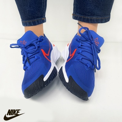 Sapatilhas Nike azuis com detalhes em vermelho, branco e preto, em fundo branco.