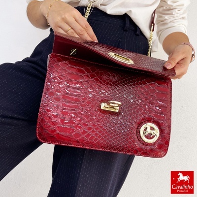 Mala vermelha de padrão pele de crocodilo com detalhes dourados e aplicação do logo Cavalinho