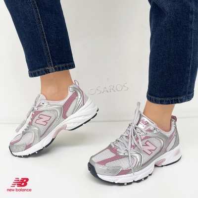 Sapatilhas New Balance rosa e prateado com sola branca e detalhes em preto.