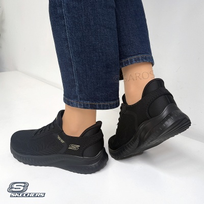 Ténis pretos desportivos Skechers usados com jeans azuis