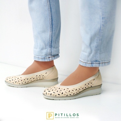 Sapatos de senhora bege com recortes e sola de cunha usados com jeans claros.