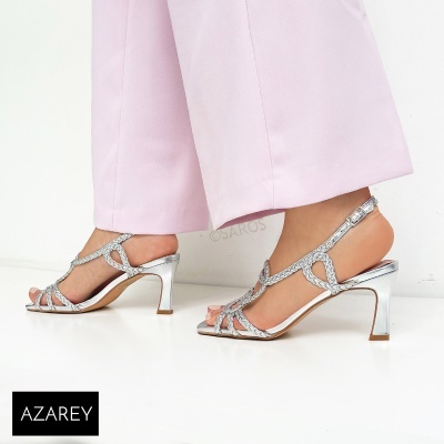 Sandálias de salto alto prateadas com tiras brilhantes e calças rosa claro