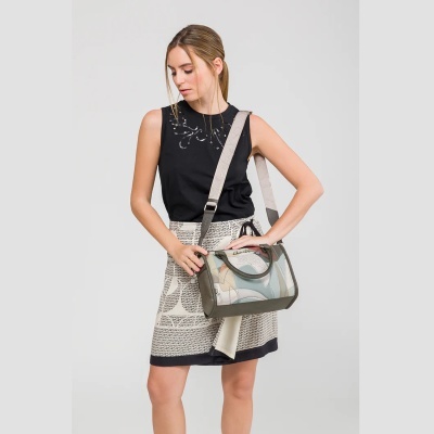 Mulher com regata preta e saia curta bege com padrão gráfico, segurando bolsa a tiracolo colorida abstrata