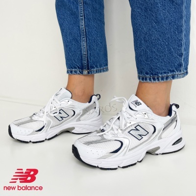 Sapatilhas New Balance brancas com detalhes cinzentos e pretos usadas com jeans azuis