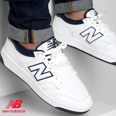 Ténis brancos New Balance com logo 'N' azul escuro e detalhes perfurados