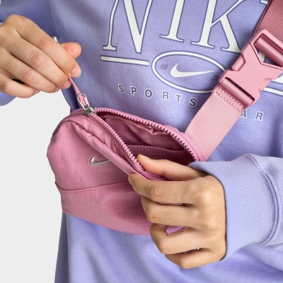 Bolsa pequena rosa Nike com fecho em mão de pessoa com camisola roxa Nike