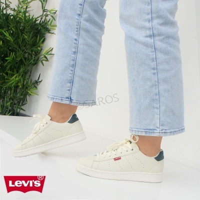 Ténis Levi's brancos com detalhes azuis, usados com calças de ganga claras em fundo branco