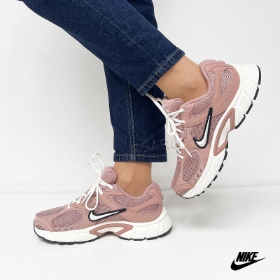 Ténis Nike rosa com sola branca e detalhes em preto usados com calças de ganga azuis.