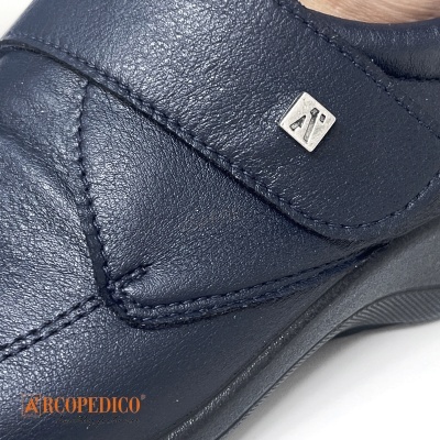 Calçado Arkopédico azul escuro com textura de pele e emblema metálico
