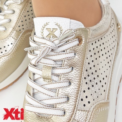 Ténis dourados com atacadores brancos e perfurações na lateral