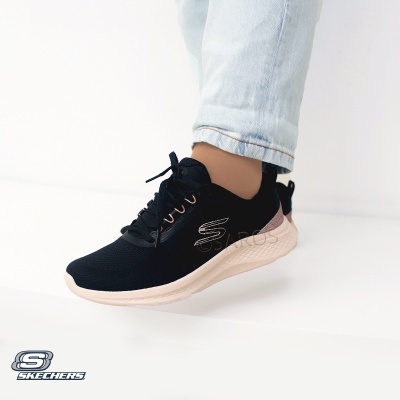 Ténis Skechers pretos com sola branca usados com calças de ganga claras