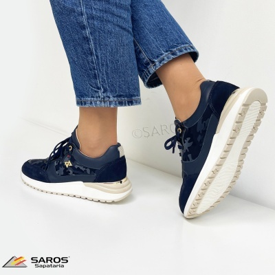 Ténis azuis escuros com sola branca usados por mulher com calças de ganga