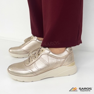 Ténis metálicos dourados com sola branca usados com calças vinho