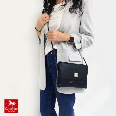 Mulher com blazer cinza, jeans azuis e mala preta Cavalinho