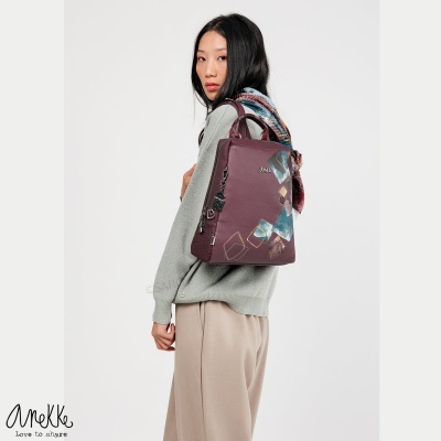 Mochila vinho com padrões geométricos coloridos e texto 'Anokke', usada por modelo com roupa casual em fundo branco.