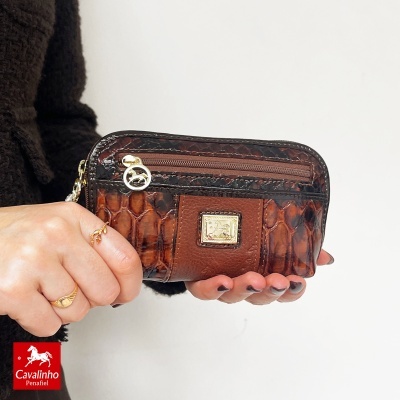 Carteira pequena em couro castanho com textura de pele de crocodilo, fecho zip e placa metálica dourada