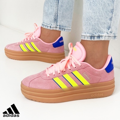 Ténis Adidas rosa com detalhes amarelos e azuis, sola castanha clara, usados com jeans
