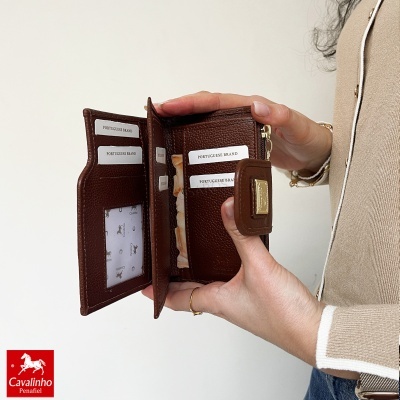 Carteira castanha em pele texturada com divisórias para cartões e porta-moedas, segurada por mãos femininas