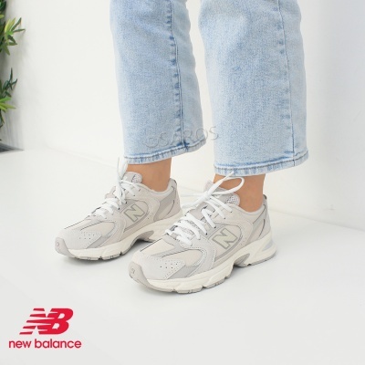 Sapatilhas New Balance cinza claro com atacadores brancos e sola branca usadas com jeans azul claro