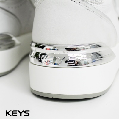 Ténis brancos com detalhe metálico prateado e escrita 'KEYS' na parte traseira