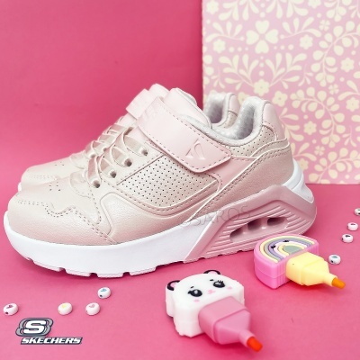 Ténis infantis rosa claro Skechers com velcro e atacadores, solado branco grosso, sobre fundo rosa com acessórios coloridos