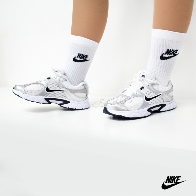 Sapatilhas Nike brancas e cinzentas com meias brancas com logótipo Nike em fundo branco