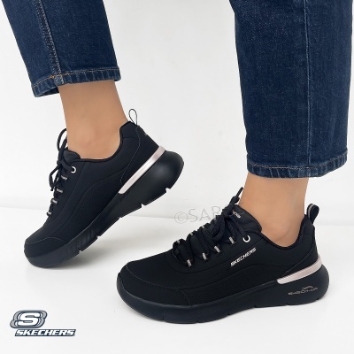 Ténis pretos Skechers com sola grossa e detalhes prateados, usados com jeans azuis.