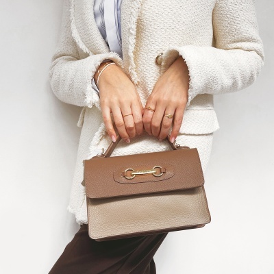 Mala de mão bege e castanha em pele com aplicação dourada CELINE PARIS, mãos segurando, pessoa vestindo casaco branco texturizado com franjas.