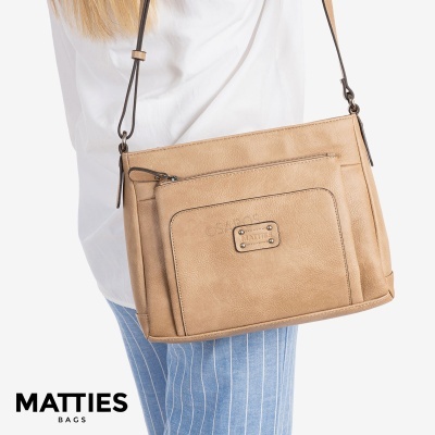 Mala de ombro bege em couro sintético com bolso frontal e placa MATTIES em modelo.