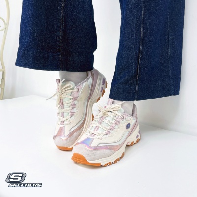 Sapatilhas Skechers creme e lilás com sola castanha e detalhes iridescentes, usadas com meias claras e calças de ganga azul escuro.