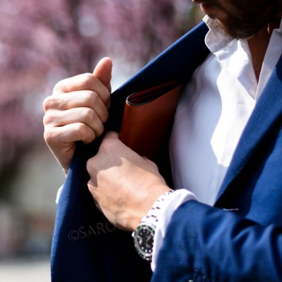 Pessoa de fato azul a colocar carteira castanha no bolso do fato