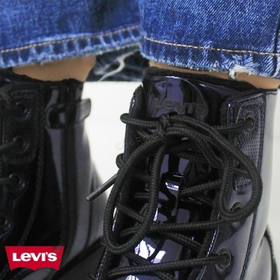 Botas pretas de verniz Levi's com atacadores pretos e calças de ganga azul.