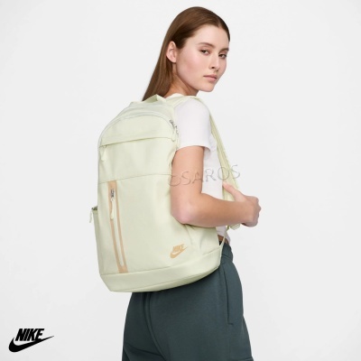 Mochila Nike creme claro com fecho bege e logótipo dourado numa modelo com t-shirt branca.