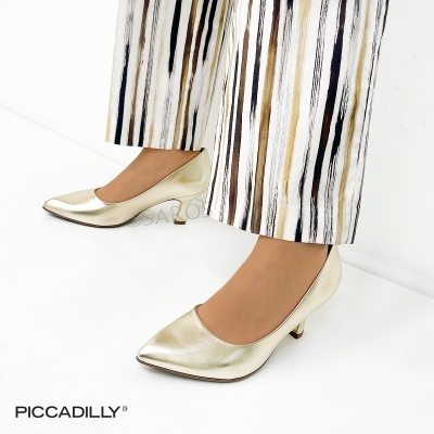 Sapatos dourados de salto médio usados com calças riscas verticais em fundo branco