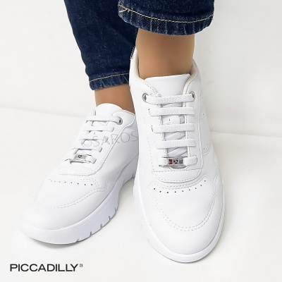 Ténis brancos em pele com atacadores brancos e solado branco usados com calças de ganga