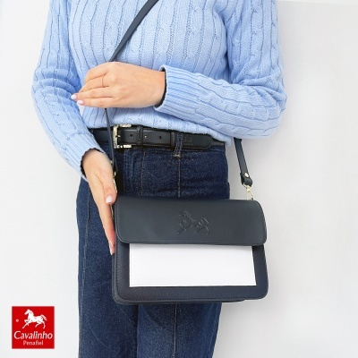 Mala de mão bicolor preta e branca com relevo de cavalo, alça preta, combinada com jeans azul escuro e camisola de malha azul clara