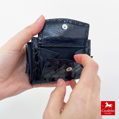 Carteira preta de pele com padrão, aberta, segurada por mãos