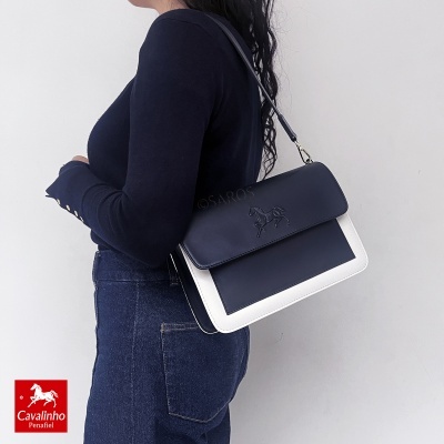 Mulher com mala Cavalinho azul e branca de pele ao ombro