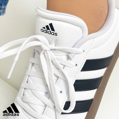 Ténis brancos Adidas com riscas pretas e sola castanha