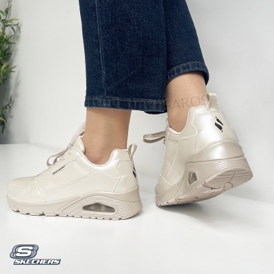 Ténis Skechers brancos com sola alta e calças de ganga azuis